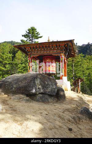 Eine farbenfrohe, traditionelle bhutanische Pagode beherbergt ein riesiges Gebetsrad mit goldenen Kalligraphie-Inschriften auf dem Weg zum Tiger's Nest Kloster Stockfoto