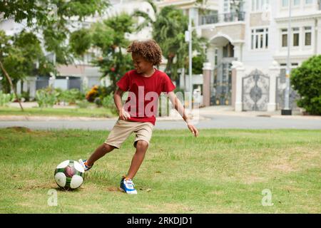 Talentiertes aktives Kind, das im Hinterhof Fußball spielt Stockfoto