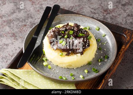 Portion of chicken liver with onions stewed in honey wine sauce with garnish mashed potatoes close-up in a plate on the table. Horizontal Stock Photo