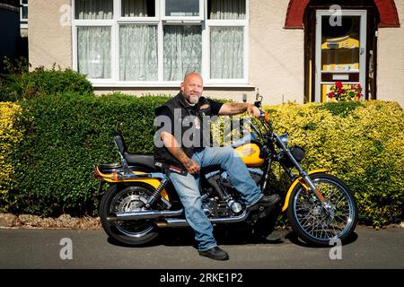 Trevor Manlow, a 53 year-old motorcycle dealer in Hillingdon, West London with his 2000 Harley Davidson Dyna Wide Glide which does not comply with ULEZ emission standards when the boundary expands. Mr Manlow is locked into a 5 year finance deal on the bike with over 3 and a half years left on the deal. Picture date: Wednesday August 23, 2023. Stock Photo