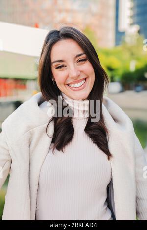 Vertical individual close up portrait of caucasian young woman smiling and looking at camera with perfect white teeth. Beautiful happy female staring front with positive and candid expression. High quality photo Stockfoto
