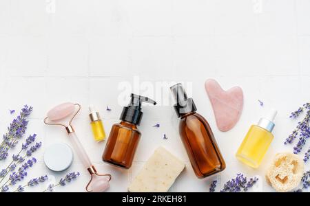 Lavendel-Spa. Natürliches ätherisches Lavendelöl und frischer Lavendel auf weißem Fliesenhintergrund. Stockfoto
