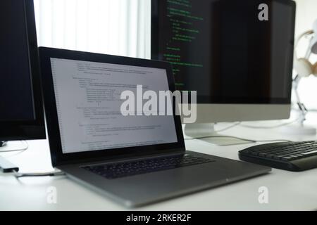 Laptop mit Programmiercode auf dem Schreibtisch des Softwareentwicklers geöffnet Stockfoto
