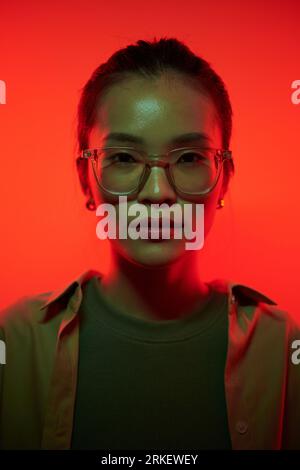 Porträt einer jungen Asienfrau in rotem Licht stehender Brille Stockfoto