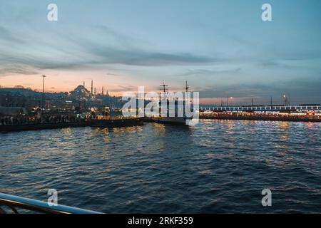 Blick auf Istanbul bei Sonnenuntergang. Galata Brücke und Fähre mit Eminonu Skyline. Istanbul Turkiye - 12.24.2022 Stockfoto