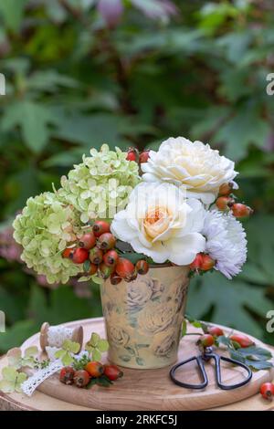 Bouquet von cremeweißen Rosen, Hortensienblüten und Rosenknospen in Vintage-Milchdose Stockfoto