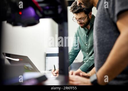 Geschäftsmann, der mit einem männlichen Kollegen im Büro steht Stockfoto