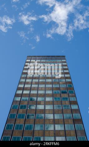 Hohes Bürogebäude steht allein unter einem sonnigen blauen Himmel Stockfoto