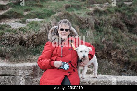 Frau, die im Winter ihren Hund am Strand umarmt Stockfoto