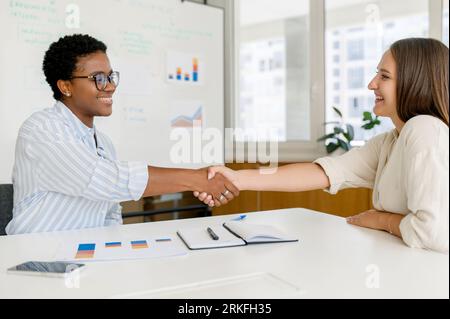 Hiring and recruitment concept. Two female office employees shaking hands in sign of good deal and cooperation, business people shaking hands, finishing up a meeting Stockfoto