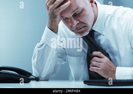 An old employee puts a gun to his throat in the midst of despair. Concept of suicide, helpless major depression, and loneliness. Loss, bereavement, la Stock Photo