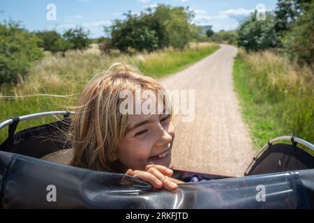 Lächelndes Mädchen, das auf einem Feldweg in Dänemark reitet Stockfoto