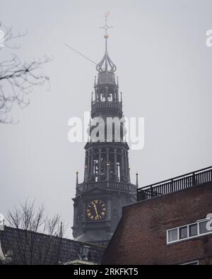 Amsterdam, Netherlands - November 27 2022: The spire and bell tower of the Oude Kerk church in Amsterdam on a foggy autumn morning. Stock Photo