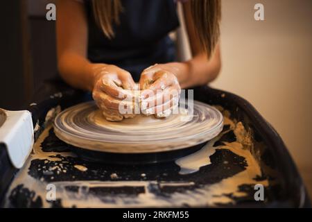 Hände eines Mädchens, die eine Schüssel auf einem Potter-Rad aus der Nähe kreieren. Tradit Stockfoto