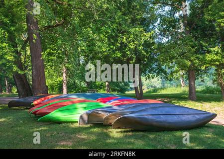 Bunte umgedrehte Kanus und Kajaks in der Nähe der St. Croix River im Interstate State Park an einem Sommermorgen in St. Croix Falls, Wisconsin, USA Stockfoto