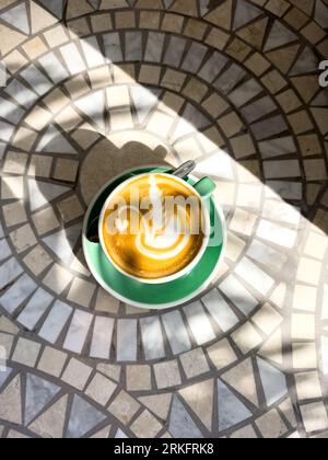 Flat white coffee in palm shadows on mosaic tiles Stock Photo