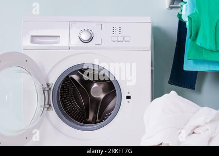 Leere Waschmaschine mit Haufen von Tuch schmutzig In den Korb Waschküche Stockfoto