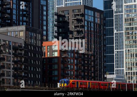 Ein Zug der Southwest Railways, der an neu errichteten Turmblöcken in Nine Elms, South London vorbeifährt. Die Turmblöcke sind Teil einer größeren Sanierung Stockfoto