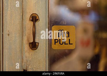 Halten Sie sich an der Tür eines Geschäfts fest und sagen Sie auf Thailändisch und Englisch „Pull“. Stockfoto