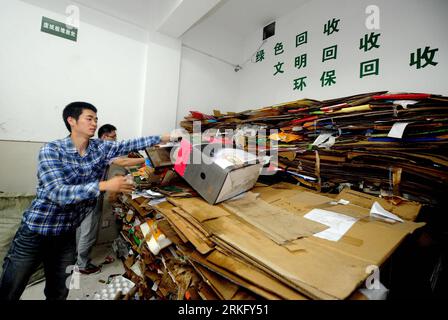 110618 -- HANGZHOU, June 18, 2011 Xinhua -- Chen Bing front clear up waste materials in a recycle depot in Hangzhou, capital of east China s Zhejiang Province, June 18, 2011. One year ago, Chen Bing, Zheng Fangzheng, Wei Bin and Chai Yu, did not seek a job after graduating from the Zhejiang University of Technology, instead, they pooled 60,000 yuan 9,200 U.S. dollars to establish a recycling company. The company is based on a new on-line recycling system to attract more young people s participation. The system gives bonus points to customers who provide waste meterials, with which they can buy Stockfoto
