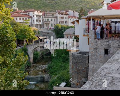 Touristen sehen von erhöhtem Aussichtspunkt über eine kleine Brücke auf dem Fluss Neretva in der Stadt Mostar, Bosnien und Herzegowina, 20. August 2023. Stockfoto