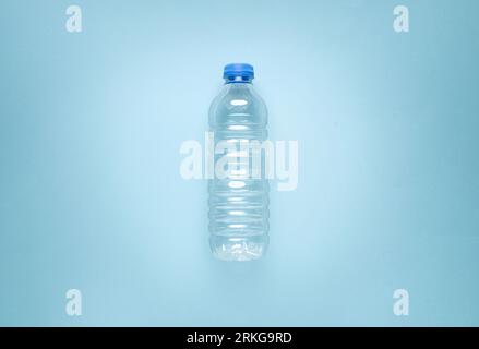 Leere Wasserflasche aus Kunststoff auf blauem isoliertem Hintergrund Stockfoto