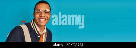 Fröhlicher afroamerikanischer Student in stylischer Jacke und Brille auf blauem Banner, Kopierraum Stockfoto