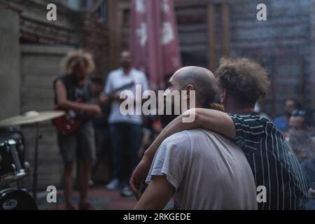 Eine Musikband, die ein lebhaftes Schauspiel auf einem Bürgersteig spielt, umgeben von einem Publikum in Tiflis, Georgia Stockfoto