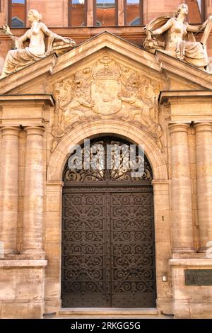 An image of two weathered stone statues standing atop an intricately decorated entranceway into a building Stock Photo