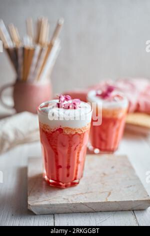 Thai-Stil geeiste rosa Milch. Kaltes süßes Getränk Red Grenadien Zuckersirup Mischung mit Milch und Eiswürfel im Glas, selektiver Fokus Stockfoto
