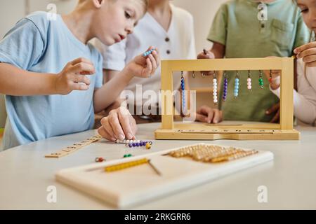 montessori school concept, multicultural children playing with color bead stairs near teacher Stock Photo