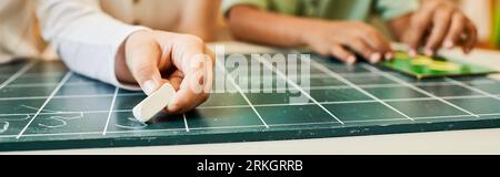 montessori-Konzept, abgeschnittene Ansicht eines Mädchens, das auf Tafel schreibt, Kreide hält, zählt, intelligent Stockfoto