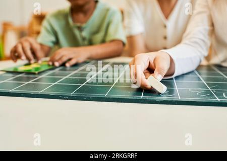 montessori concept, multicultural children, girl writing on chalkboard near teacher and african boy Stock Photo