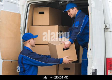 Junge Lieferung Männer entladen Kartons vom Lkw Stockfoto