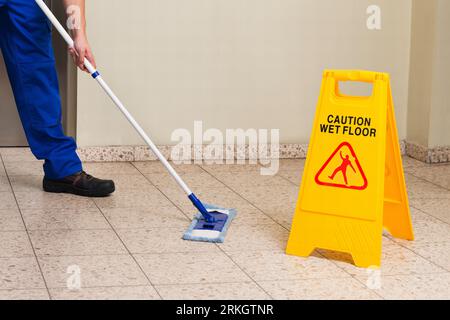 Gerne männliche Hausmeister mit der Reinigung der Geräte Boden wischen Stockfoto