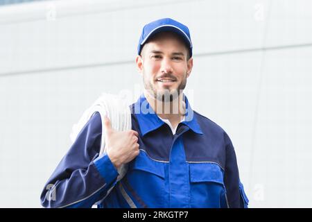 Lächelnd Handwerker mit Toolbox und Kabel Vor Fahrzeug Stockfoto