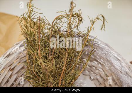 A white wicker basket containing a glass jar filled with ice and topped with a small sprig of rosemary Stock Photo