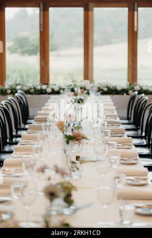 Ein Hochzeitstisch mit verschiedenen Glaswaren und farbenfrohen Blumenarrangements Stockfoto