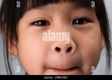 Ein Foto von einem süßen Mädchen im Vorschulalter, das ein lustiges, dummes Gesicht macht. Stockfoto