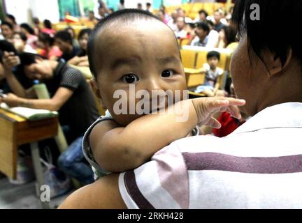 Bildnummer: 55682045  Datum: 06.08.2011  Copyright: imago/Xinhua (110806) -- SHANGHAI, Aug. 6, 2011 (Xinhua) -- Cheng Hongbing, an eight-month-old baby, rests with his family in a shelter as Typhoon Muifa is approaching in east China s Shanghai Municipality, Aug. 6, 2011. Over 3,800 who live in the shanty towns and construction sites were moved to the shelters for safety reasons.(Xinhua/Chen Fei) (xzj) CHINA-SHANGHAI-TYPHOON MUIFA-PEOPLE TRANSFER (CN) PUBLICATIONxNOTxINxCHN Gesellschaft Unwetter Wetter Sturm Taifun Schutz Armut Notunterkunft Schutzraum premiumd xbs 2011 quer o0 Bevölkerung, Ki Stock Photo