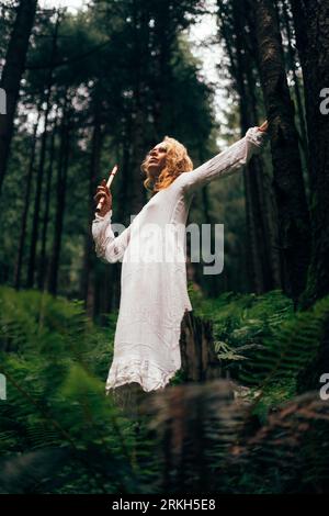 A female standing in a forest with a flute in her hand Stock Photo