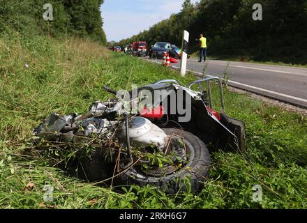 Schongau, Deutschland. 25. August 2023. Beschädigte Motorroller liegen an der Bundesstraße 17 um ein zerstörtes Auto herum. Nach Angaben der Polizei wurden bei einem Unfall mit zwei Autos und einer Gruppe von Motorrädern in Oberbayern mehrere Personen, einige davon schwer verletzt. Quelle: Karl-Josef Hildenbrand/dpa/Alamy Live News Stockfoto