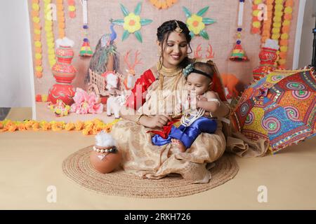 Janmashtami-Konzept. Mutter sitzt mit ihrem süßen Jungen, der als kleine krishna verkleidet ist. Stockfoto