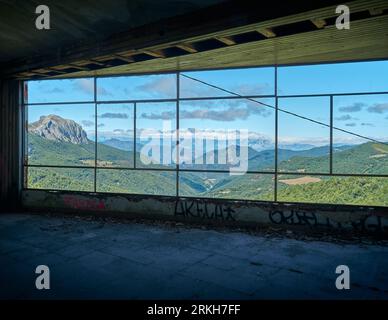 Berglandschaft durch ein Fenster gesehen, ruiniertes Gebäude mit einem Fenster ohne Glas mit Blick auf ein Bergtal mit hohen Gipfeln und Wolken Stockfoto