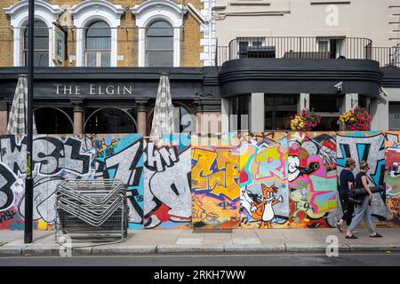 London, Großbritannien. 25. August 2023. Vor dem Notting Hill Carnival kommen die Menschen an einem Pub vorbei, denn Europas größtes Straßenfest, das die karibische Kultur feiert, soll täglich über 1 Million Menschen willkommen heißen. Es wurde auch berichtet, dass Kensington und Chelsea Council ein Wochenende für 41 ältere und gefährdete Erwachsene finanziert haben, die auf der Karnevalsroute leben und während der Feierlichkeiten möglicherweise Schwierigkeiten haben, ihre Immobilien zu verlassen Stockfoto