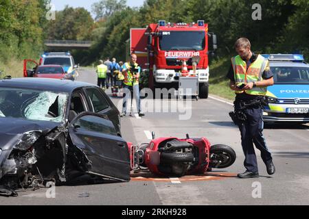 Schongau, Deutschland. 25. August 2023. Ein beschädigter Motorroller (M) liegt an der Bundesstraße 17 neben einem zerstörten Auto. Nach Angaben der Polizei wurden bei einem Unfall mit zwei Autos und einer Motorradgruppe in Oberbayern mehrere, teilweise schwer verletzte Personen verletzt. Quelle: Karl-Josef Hildenbrand/dpa - ACHTUNG: Kennzeichen wurden aus rechtlichen Gründen pixeliert/dpa/Alamy Live News Stockfoto