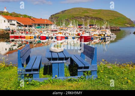 Seats on waterfront with colourful fishing boats in village harbour. Kamoyvaer, Magerøya island, Honningsvar, Troms og Finnmark, Norway, Scandinavia Stock Photo