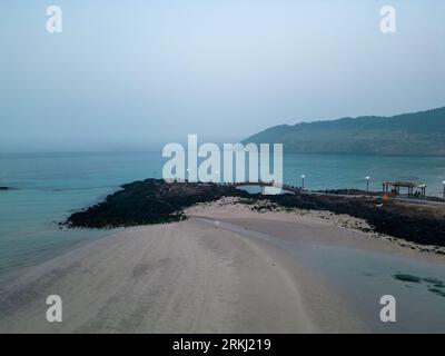 A tranquil beach scene featuring a large expanse of ocean shoreline with white sand and crystal blue waters Stock Photo