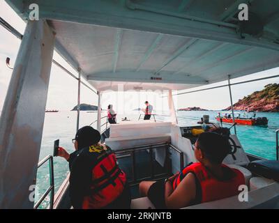 A group of tourists wearing a life jackets and snorkeling gear on a boat during their vacation Stock Photo