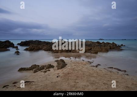 Lange Exposition der Felsen am Strand mit einem bedeckten Himmel Stockfoto